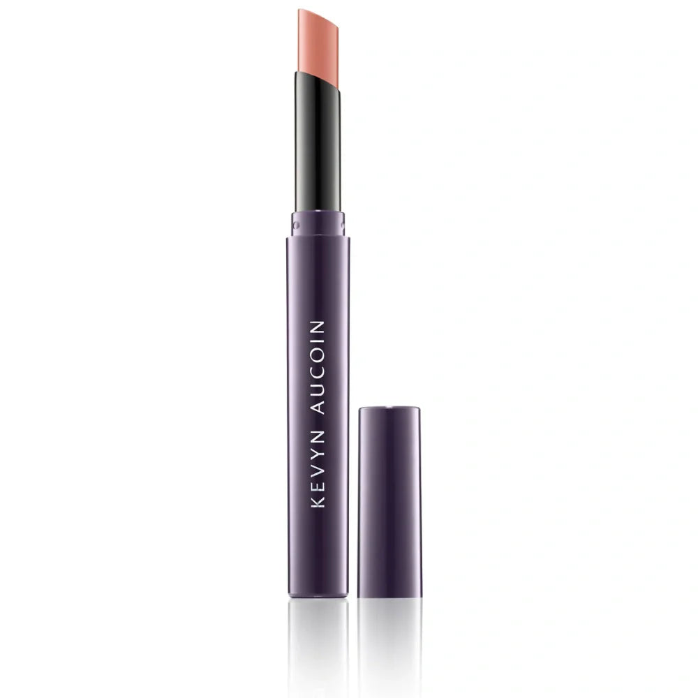 Cream lipstick in a coral-pink shade, with black cap and purple tube.
