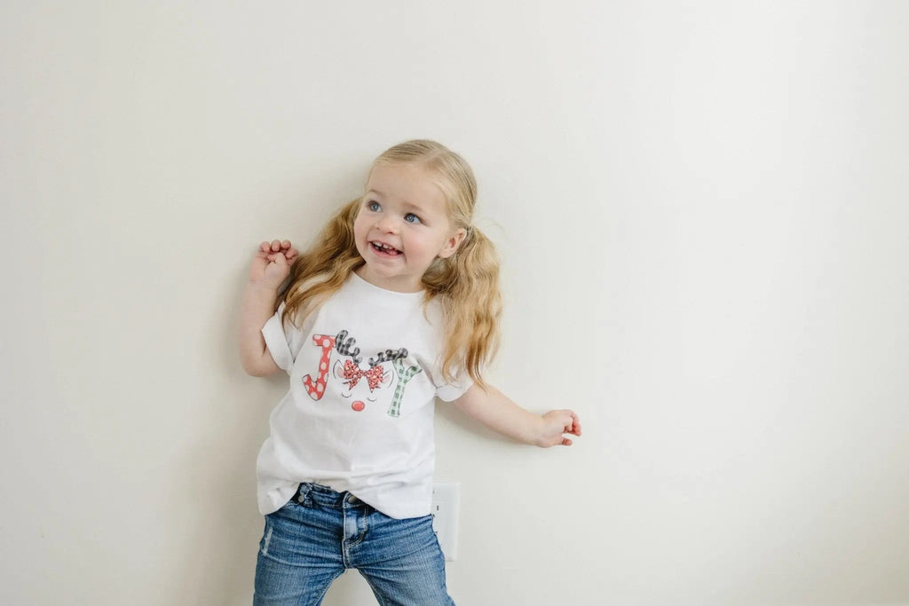 Young child wearing a white t-shirt with a colorful reindeer graphic
