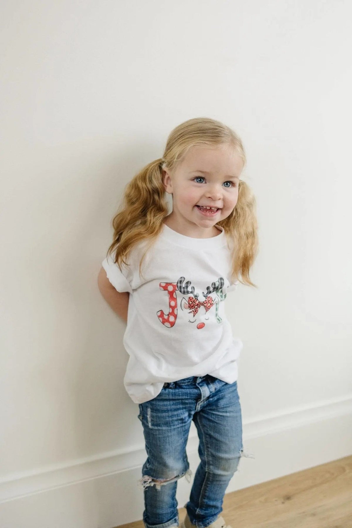 Kids white t-shirt with colorful reindeer front graphic, worn with blue jeans