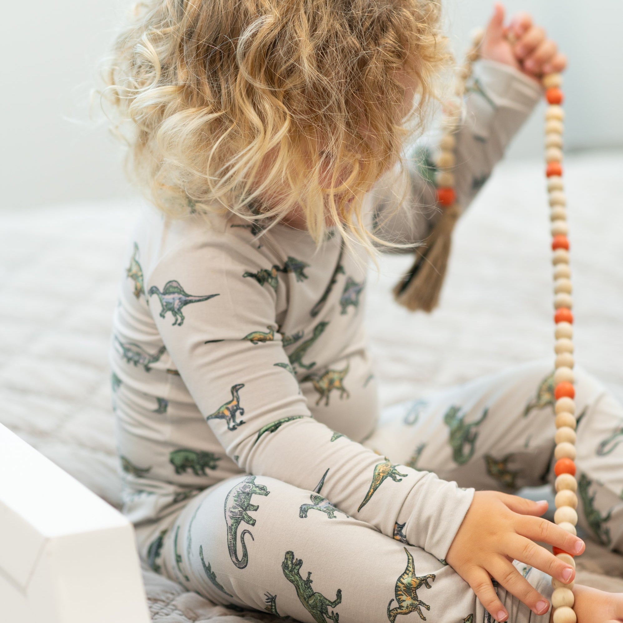 Light gray dinosaur-print pajama set with long sleeves and cuffed cuffs