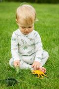 White dinosaur-print baby romper with long sleeves and footed legs