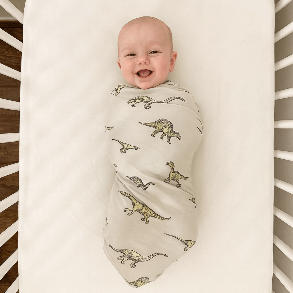 Baby swaddle blanket in cream with green dinosaur print, newborn wrapped