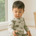 Infant zipper footie in light gray with green dinosaur print and long sleeves