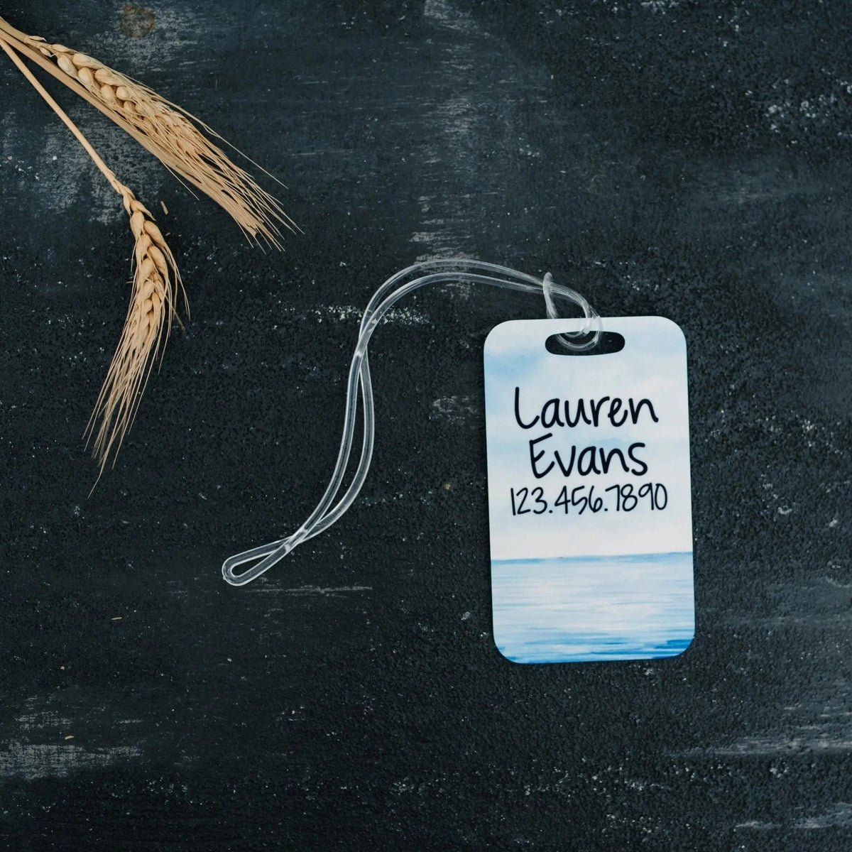 Ocean-themed luggage tag with Lauren Evans and 123.456.7890; white hanging cord loop