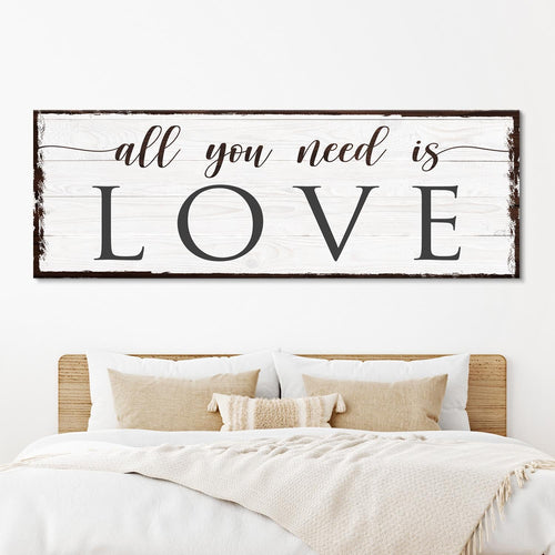 Wall sign reading “all you need is LOVE” on whitewashed wood frame