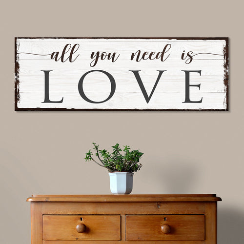 Wall sign reading “all you need is LOVE” on whitewashed wood plank frame