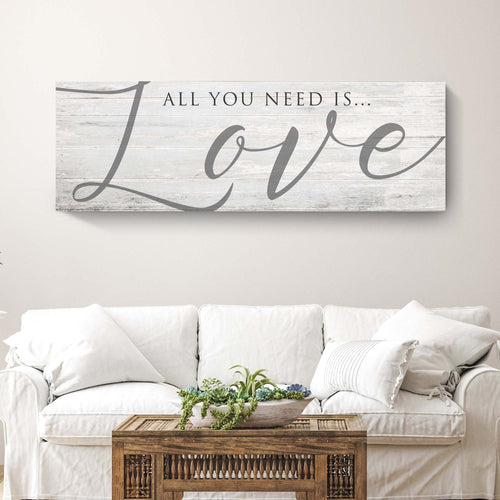 Light wood plank Love wall canvas sign with “All you need is…” and cursive “Love”