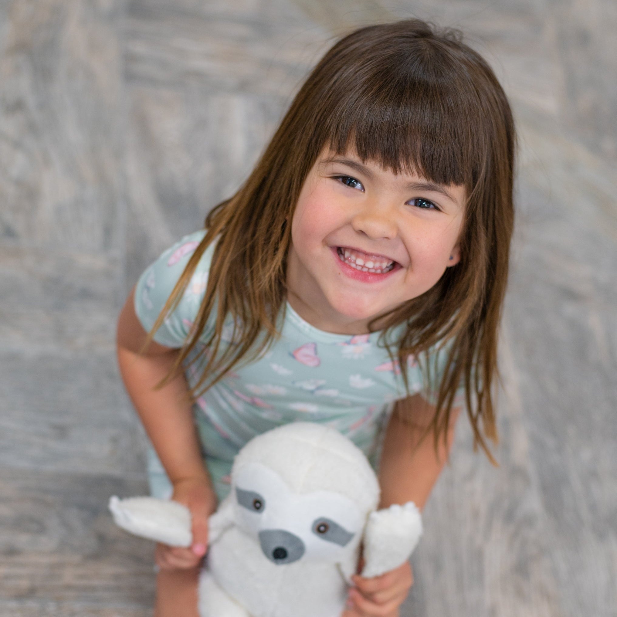 Girls mint short-sleeve pajama top with butterfly and daisy print, holding a plush dog