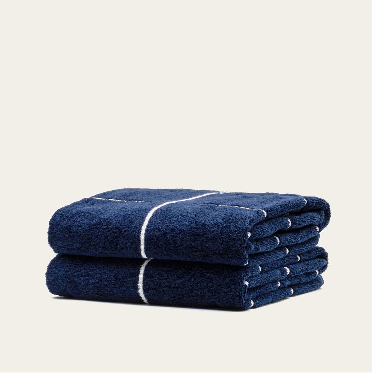 Rolled navy cotton towel with white stripe band, stacked with a second towel