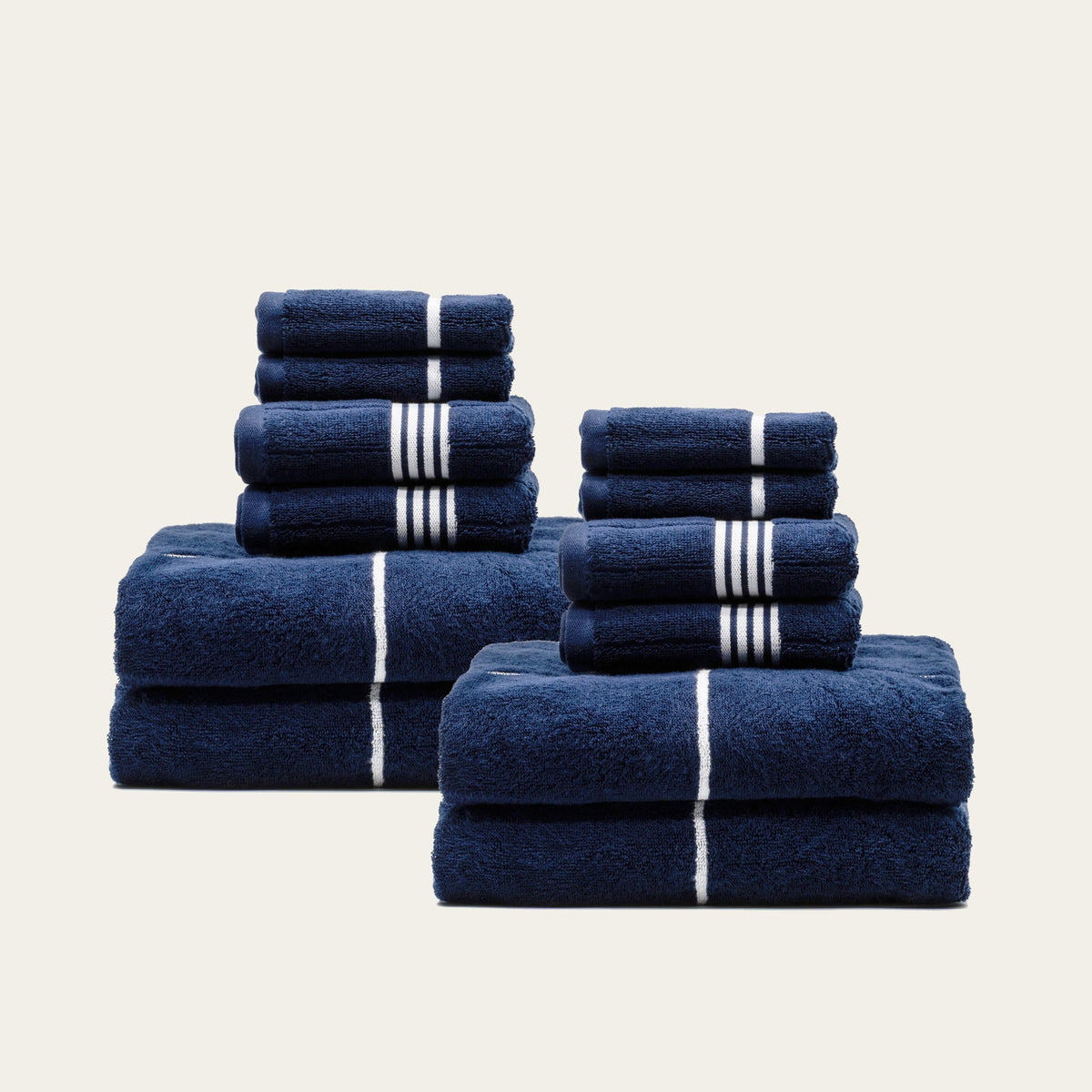 Navy cotton towels with white stripe bands, folded and stacked in two groupings