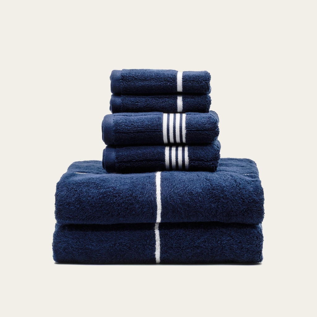 Navy cotton towel stack with white center stripe bands, neatly folded