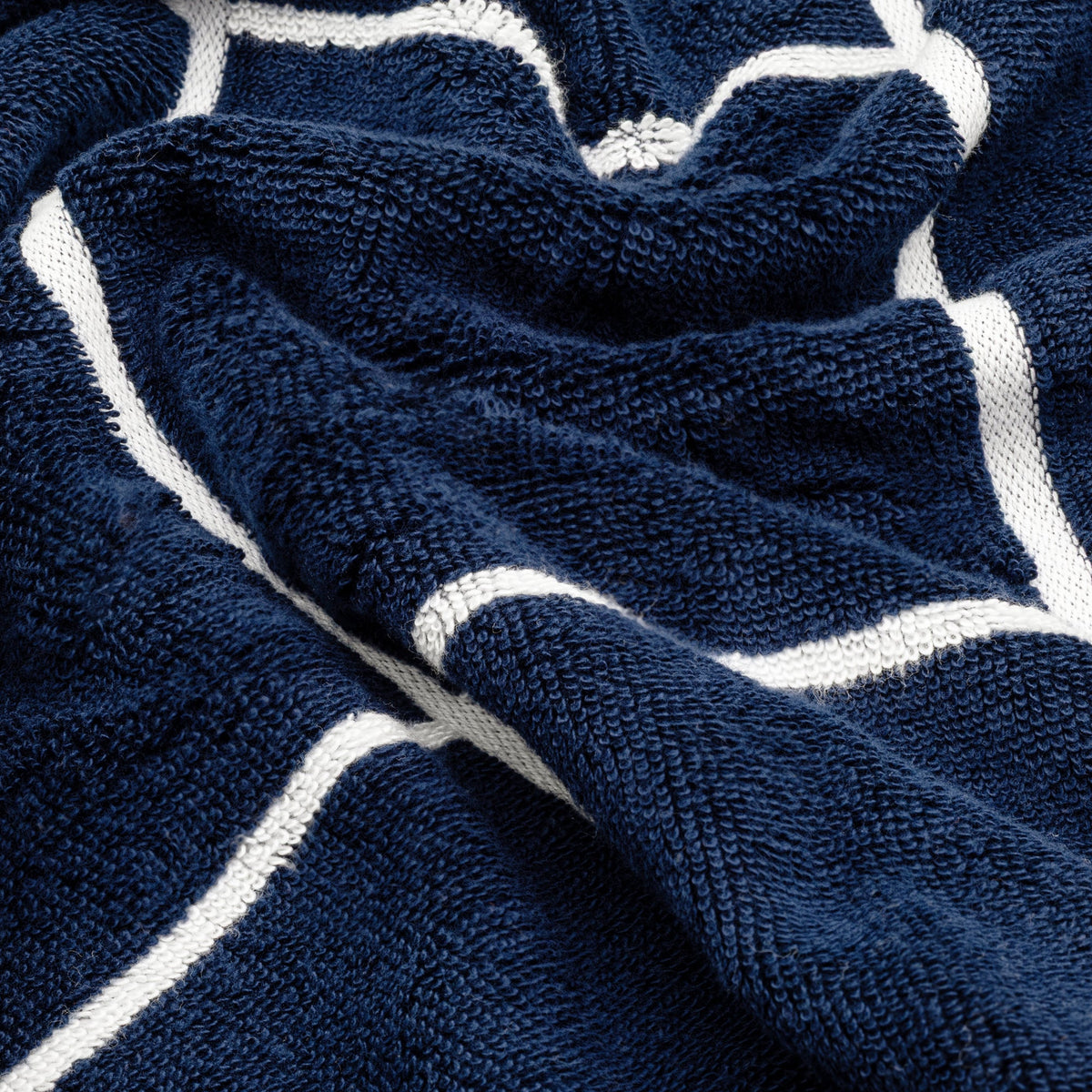 Close-up of navy cotton towel texture with white stripe grid accents