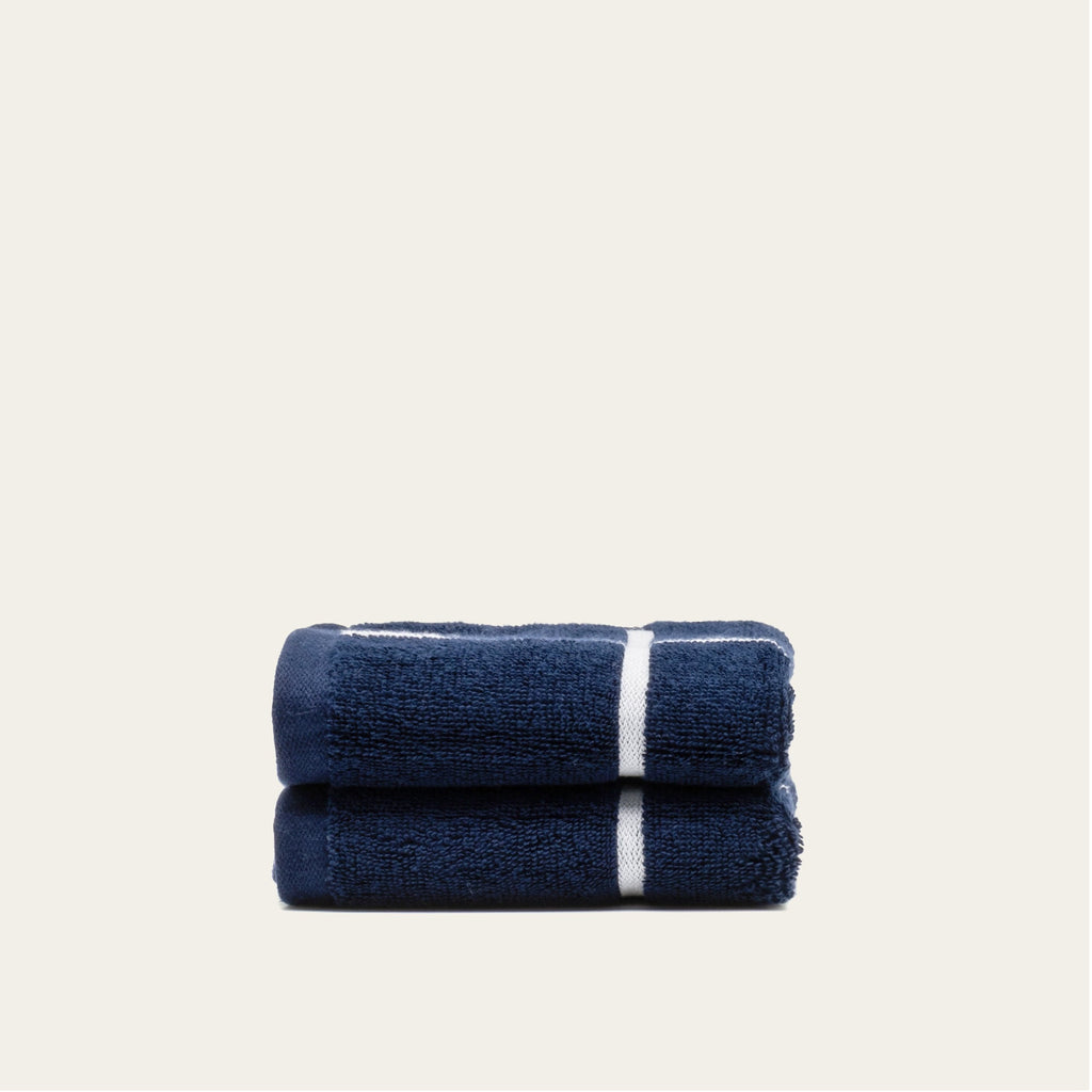 Folded navy cotton towels with white center stripes, stacked set of 2