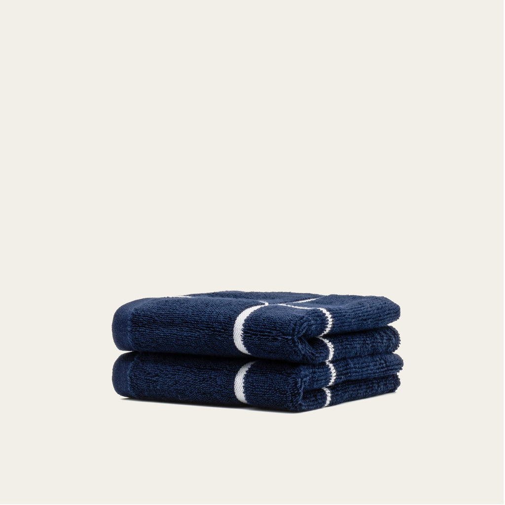 Rolled navy cotton towels with white stripe band, stacked set