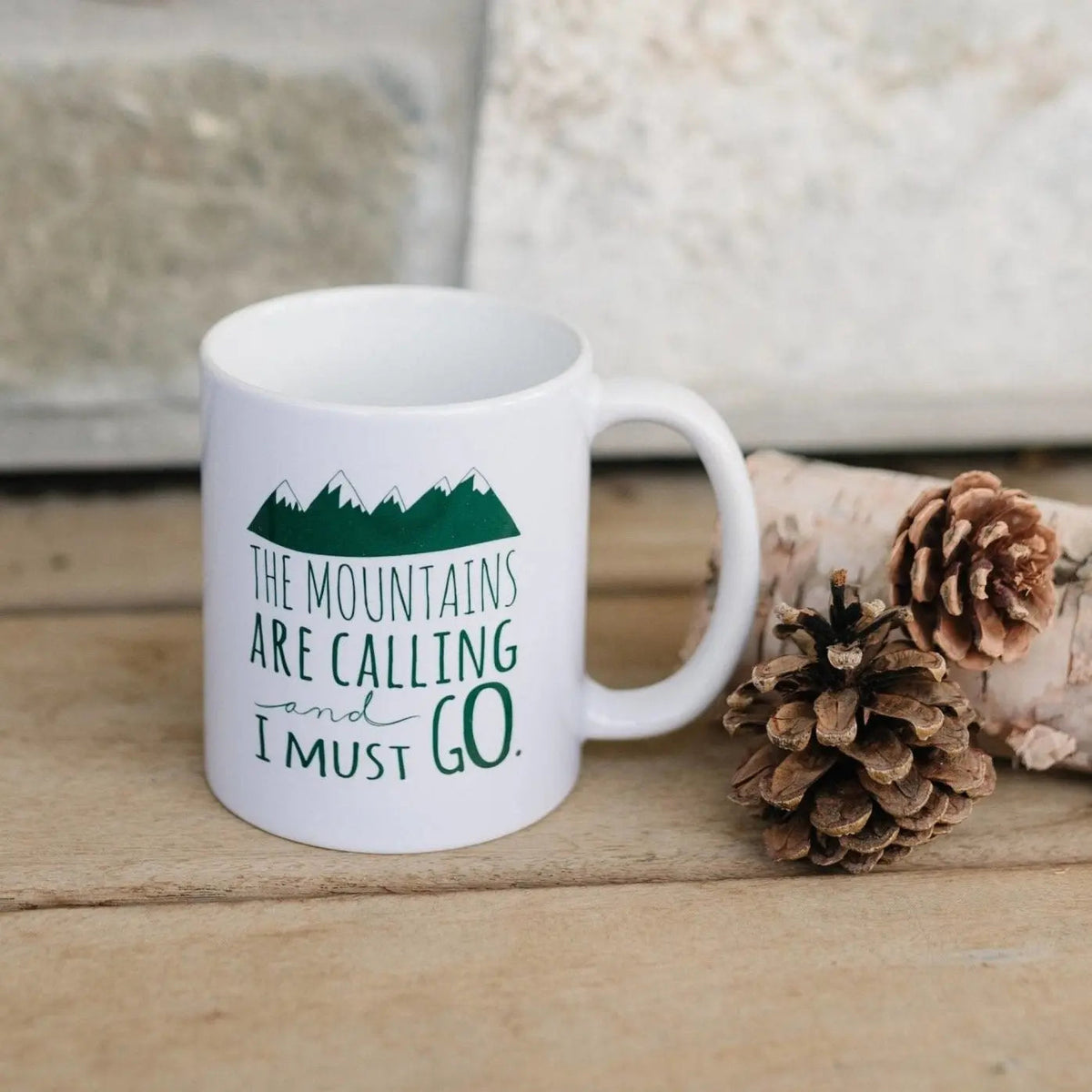 White ceramic coffee mug with green mountain quote and tree graphic on front