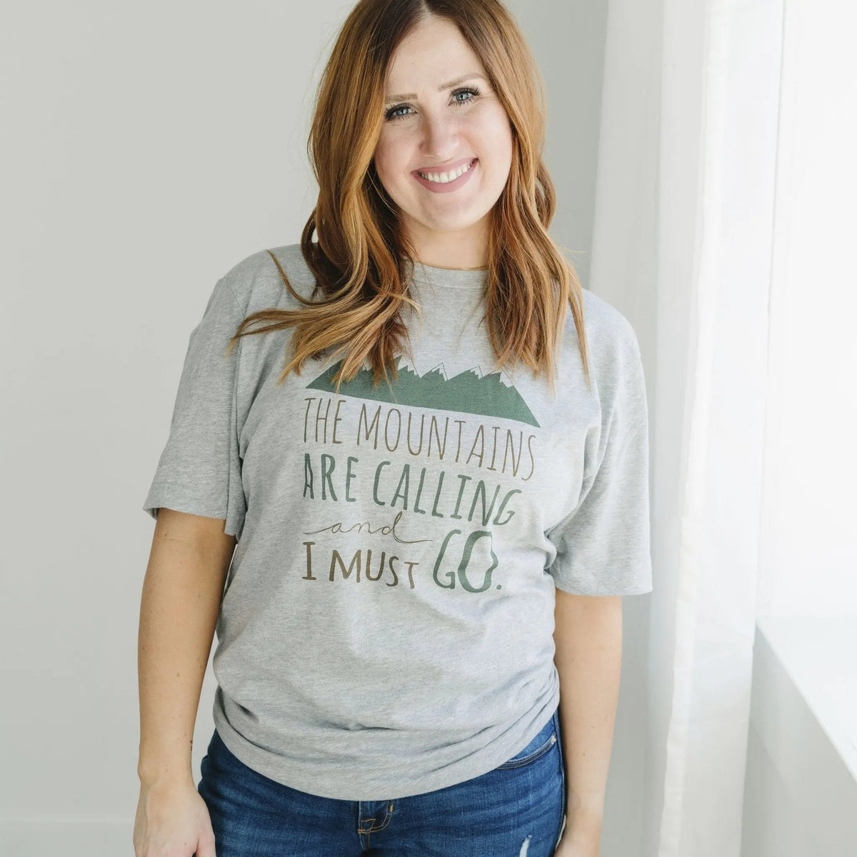 Gray unisex t-shirt with green mountain graphic and “The mountains are calling”
