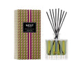 Glass reed diffuser with black reeds, green label, and geometric green-and-brown gift box