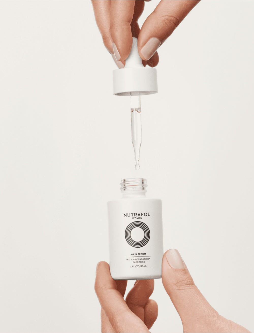 Nutrafol hair serum bottle with dropper releasing clear liquid