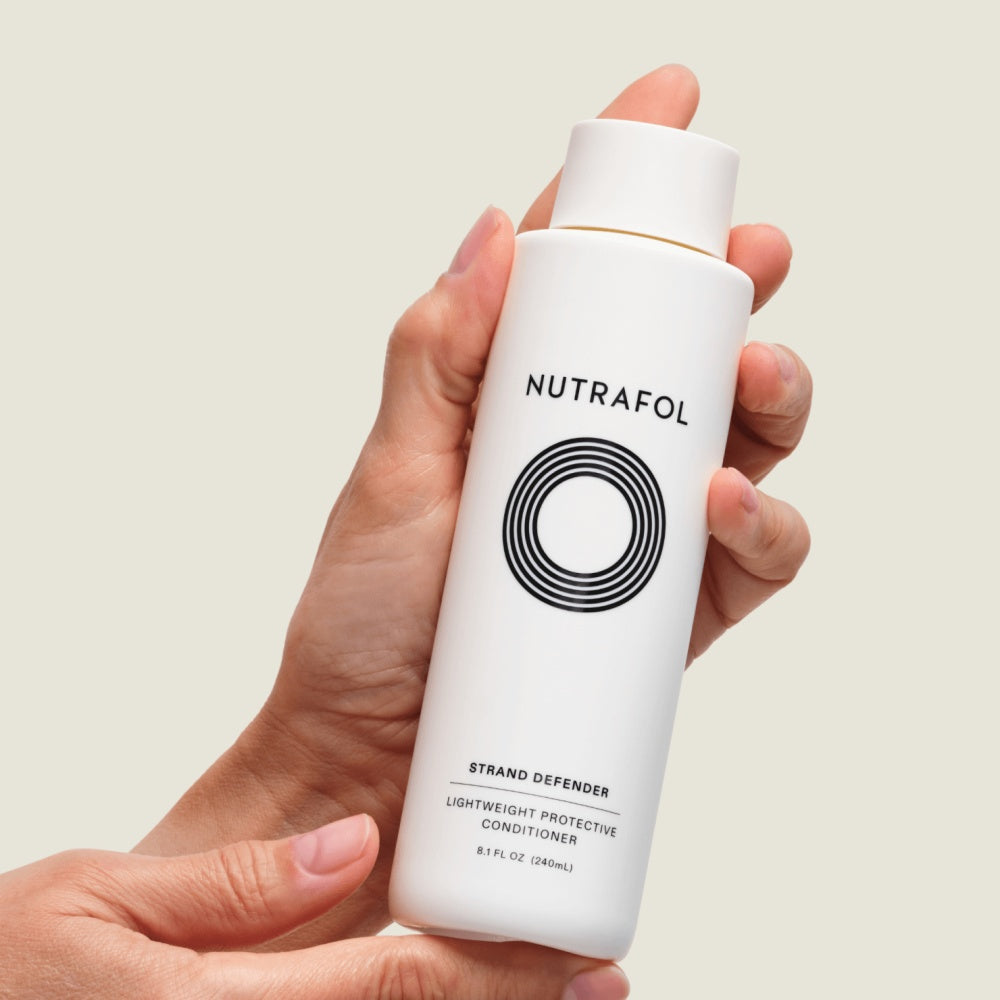 NUTRAFOL Strand Defender lightweight protective conditioner bottle held in hand