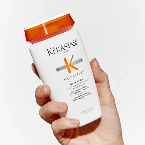 Hand holding shampoo bottle with orange cap and Kerastase Nutritive label