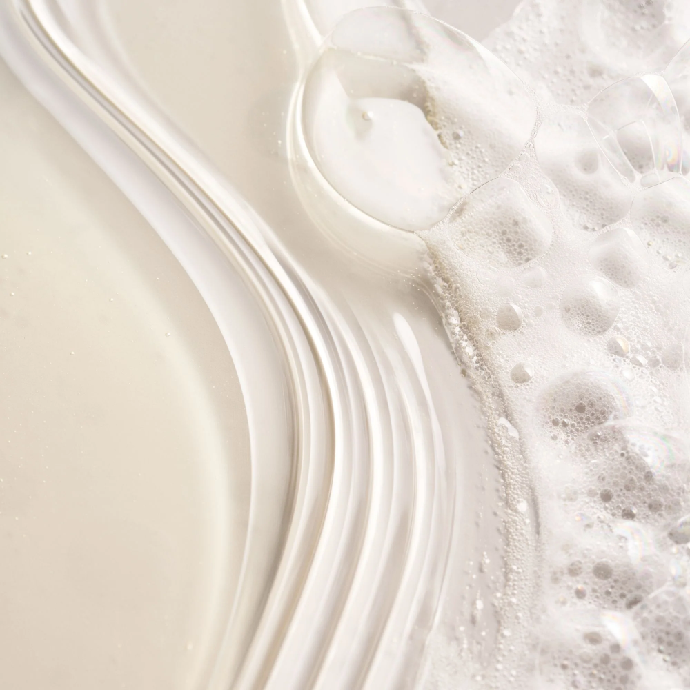 Foamy shampoo lather swirling on a smooth surface with creamy bubbles