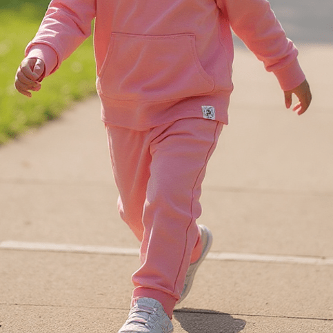 Pink hooded jogger set worn while running, front pocket hoodie and tapered jogger pants