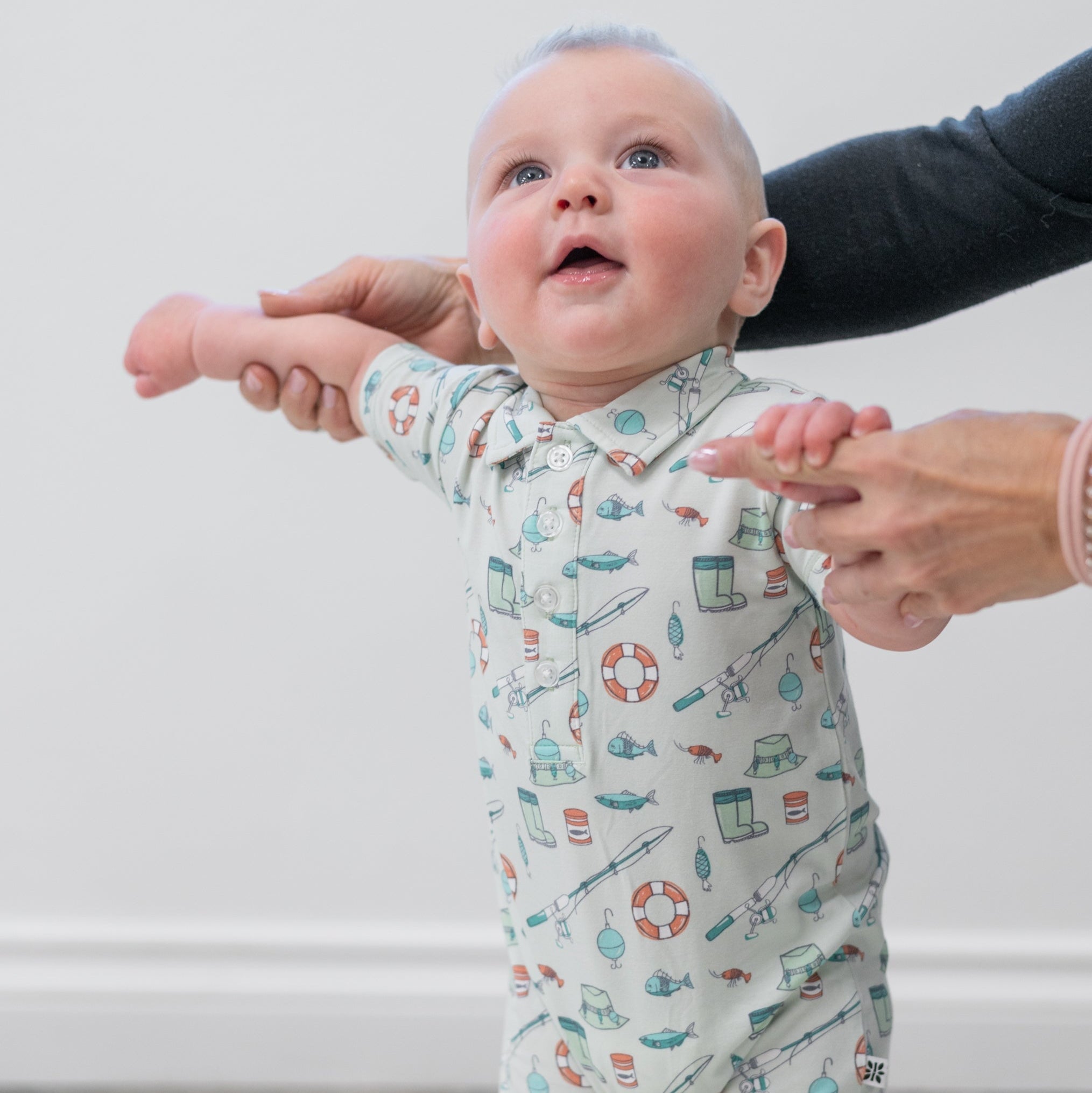 Baby fishing romper front view, light cream with allover teal and orange fishing print