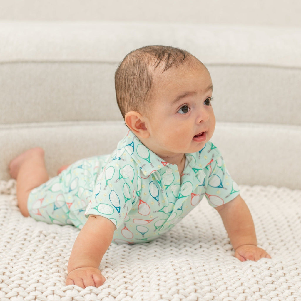 Turquoise polo romper for boy, short sleeves, button collar, tennis racket pattern.