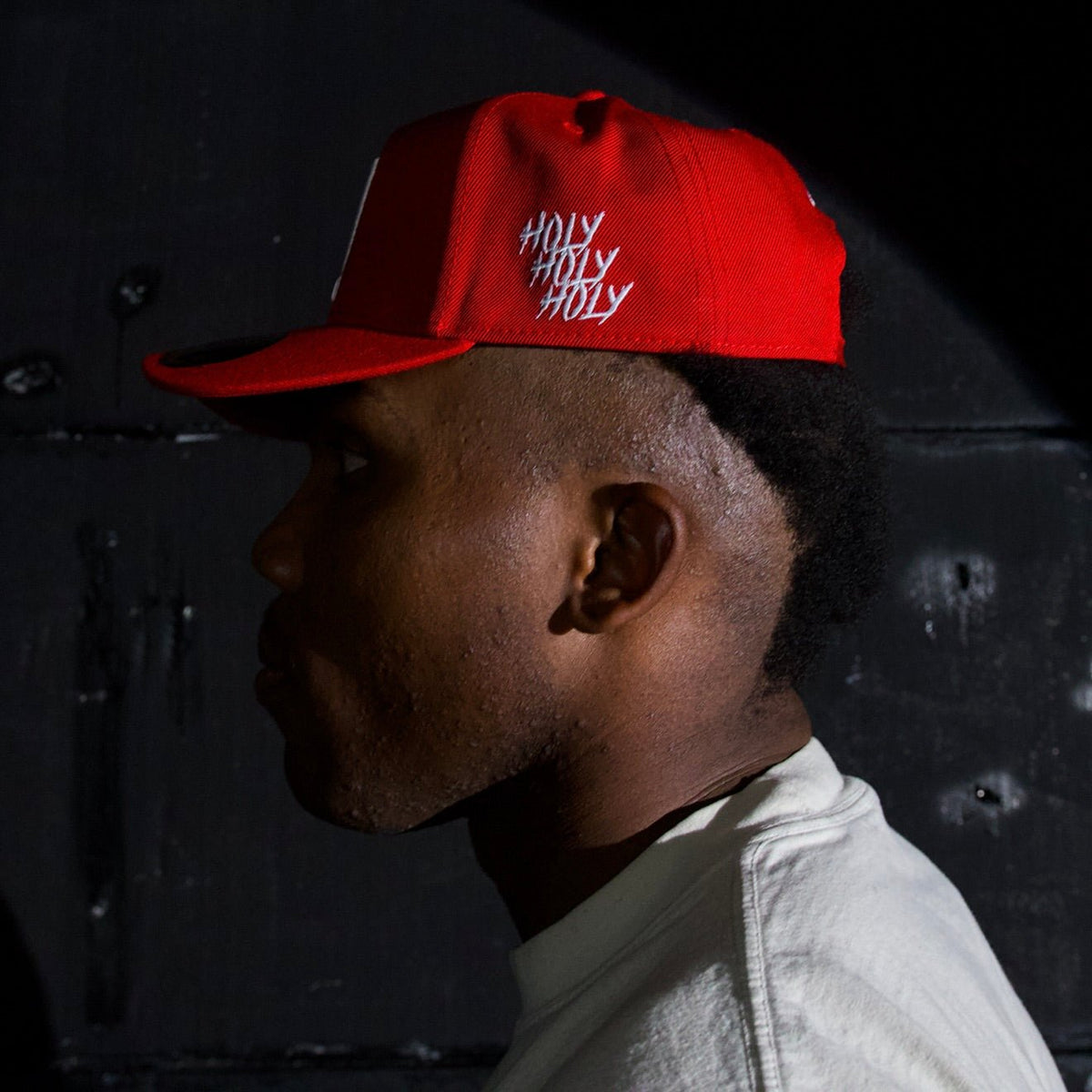 Red snapback cap with white embroidered 'HOLY' logo and curved brim