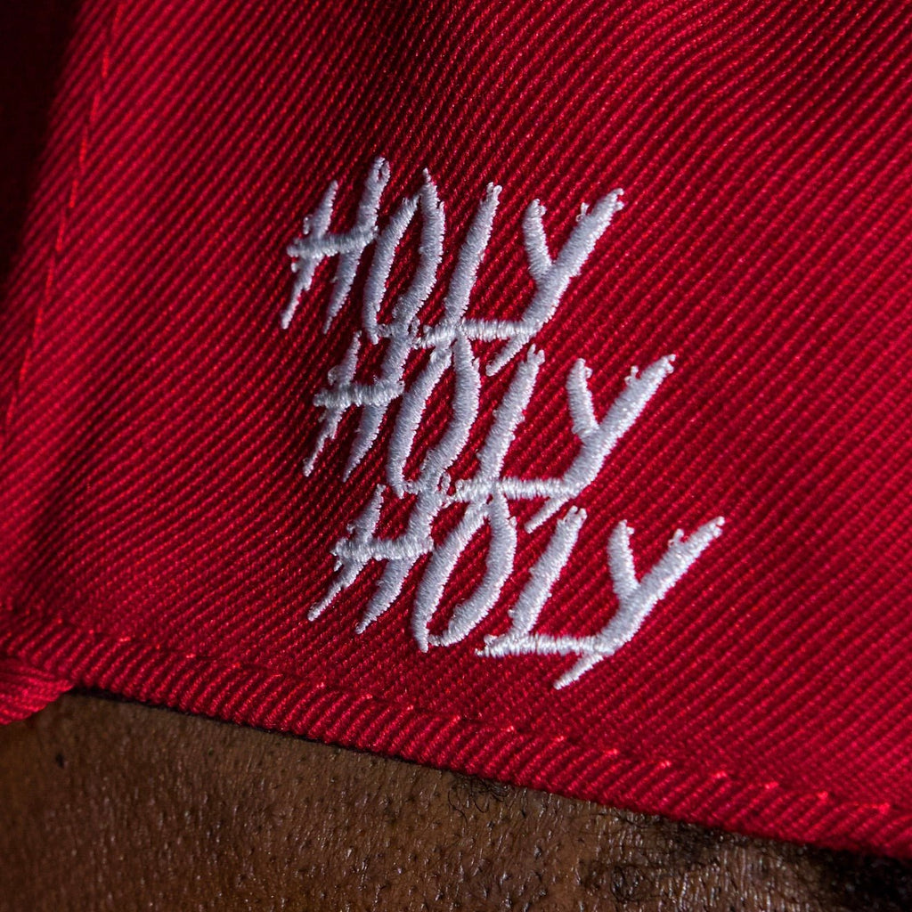 Close-up of white hashtag-style text on red snapback cap fabric