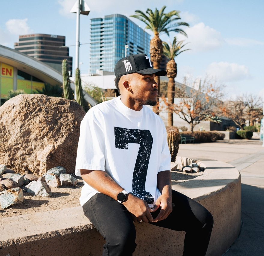 Black snapback cap with white '7' patch, worn outdoors