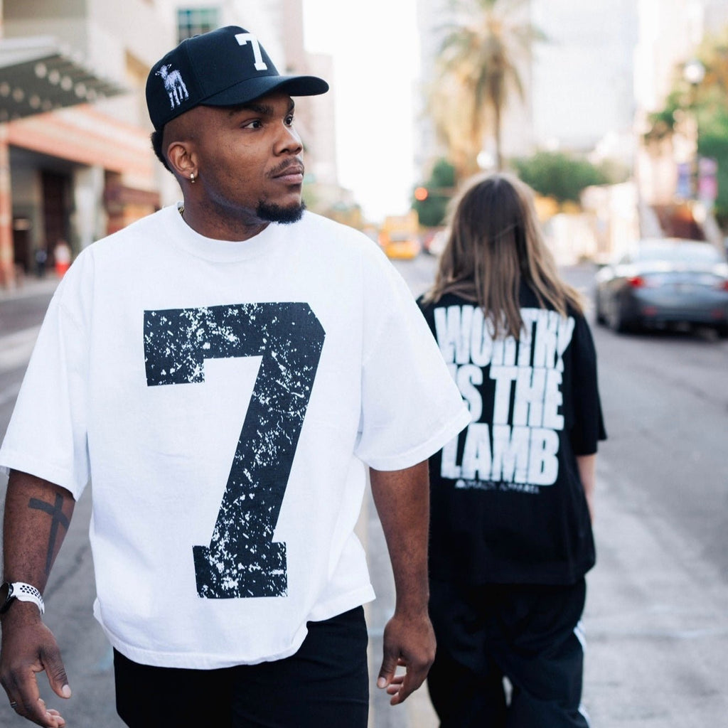 Black snapback cap with white '7' patch worn on city street
