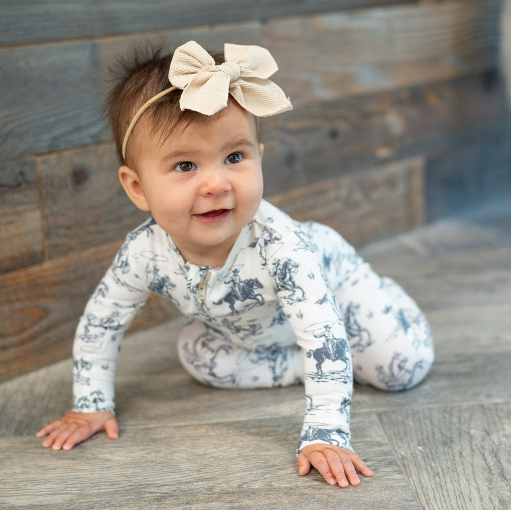 White cowboy-print zip-front footie worn by baby crawling, long sleeves and cuffs
