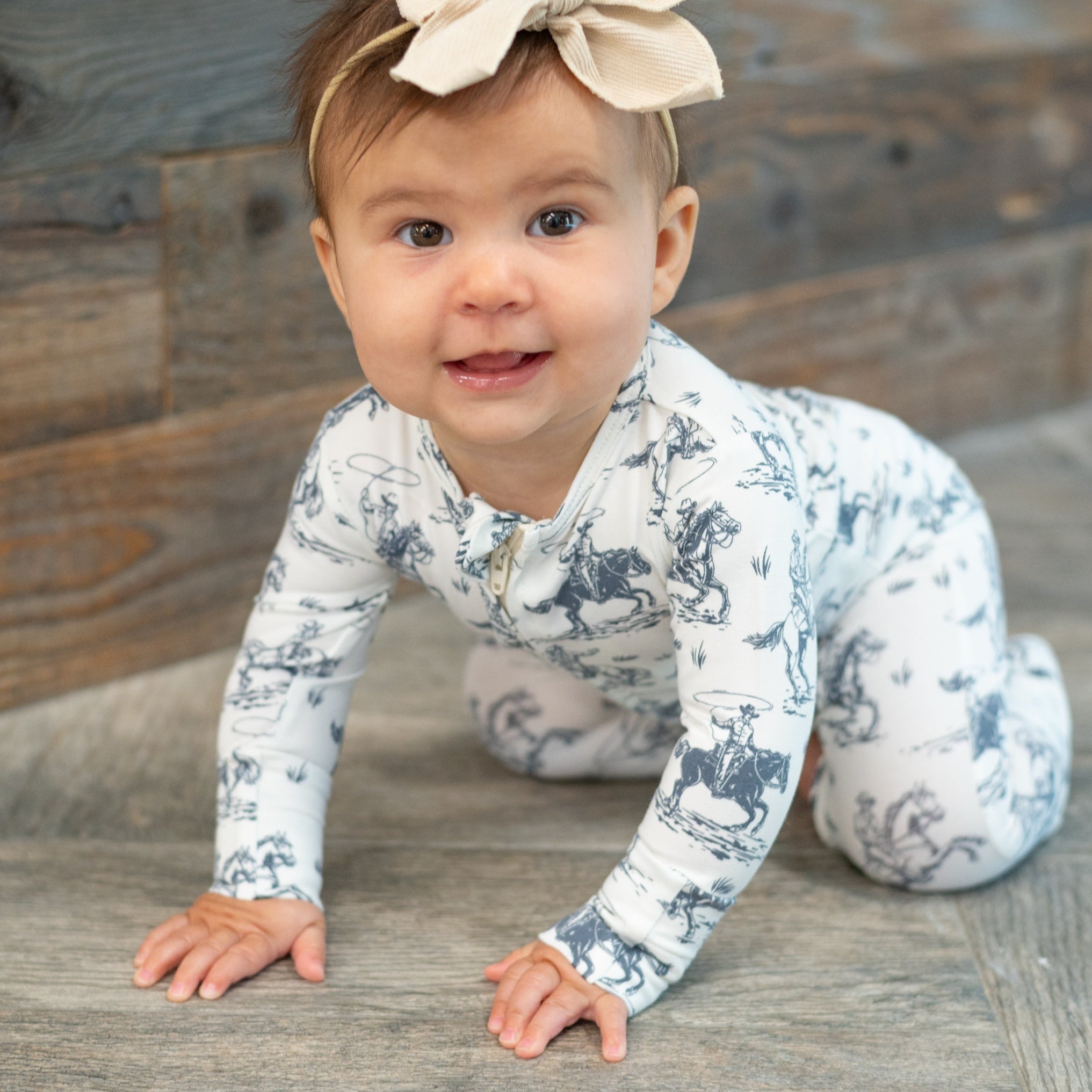 White cowboy-print zip-front footie worn by baby, long sleeves and ankle cuffs