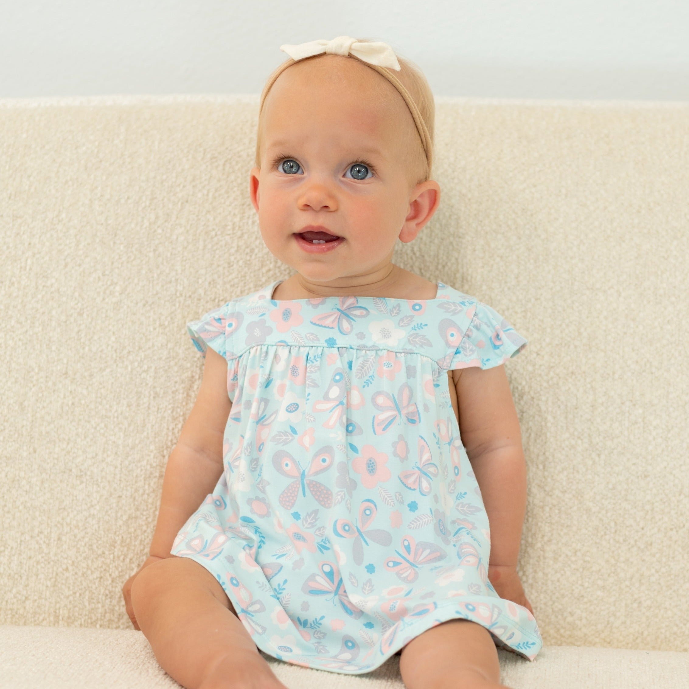 Ruffled aqua baby dress with matching bloomer shorts, front view with butterfly and animal print