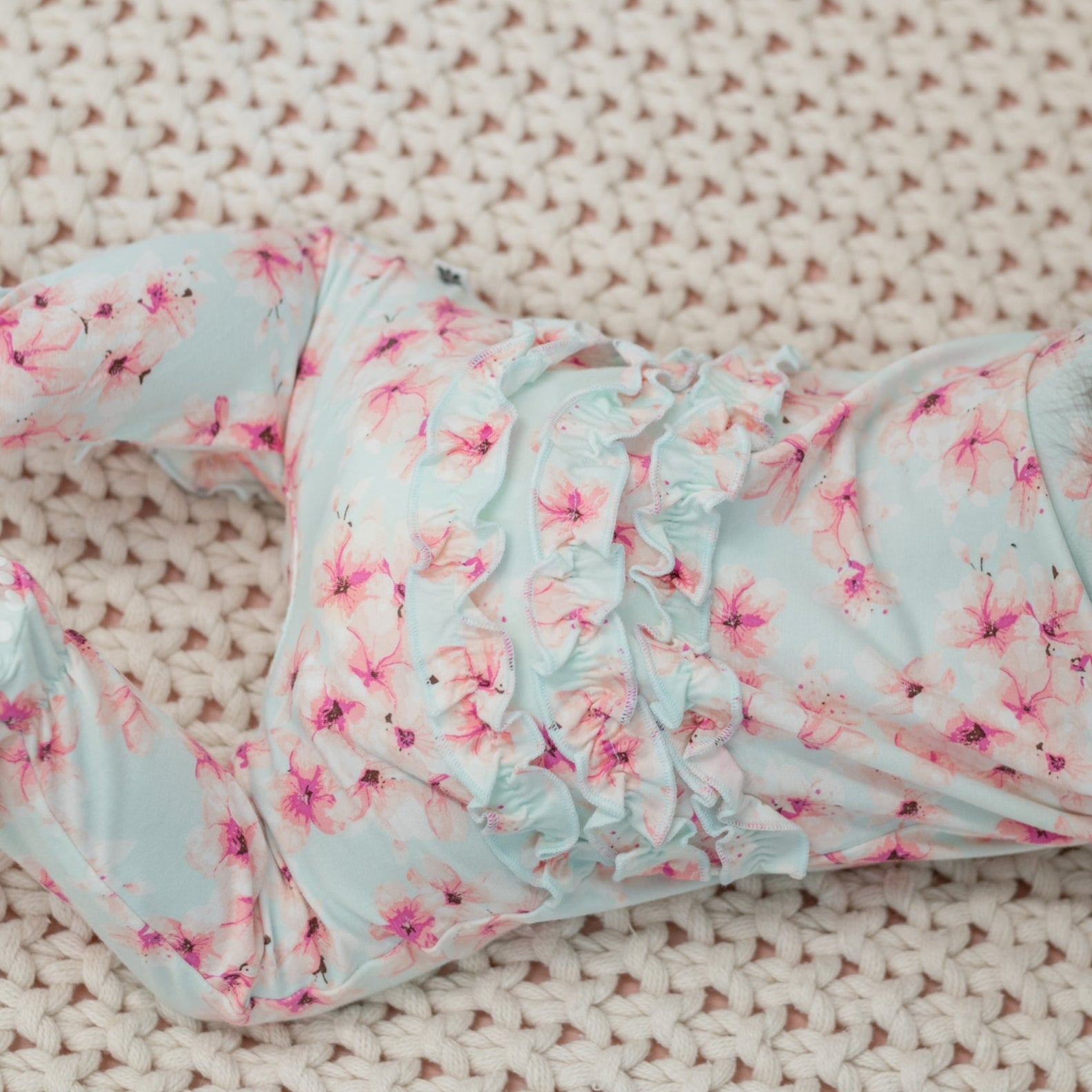 Blue floral ruffle footie with gathered neckline and cuff details