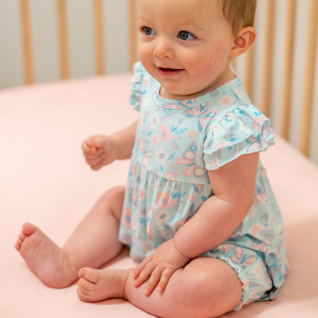 Light aqua ruffle romper with flutter sleeves and bird-and-butterfly print, baby seated