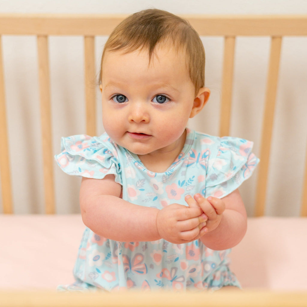 Light aqua ruffle romper with flutter sleeves and bird-and-butterfly print, baby arms out