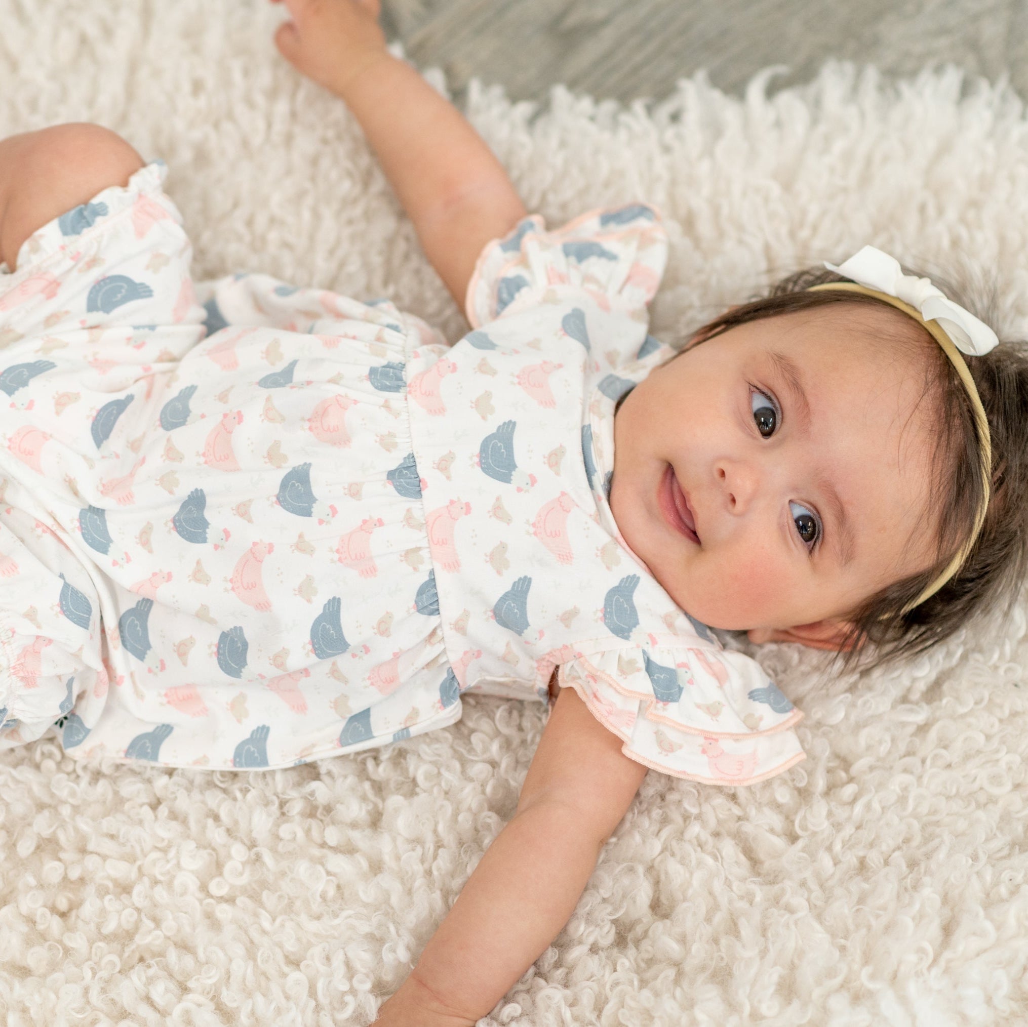 Baby girl romper in pastel bird print with ruffled sleeves and short legs