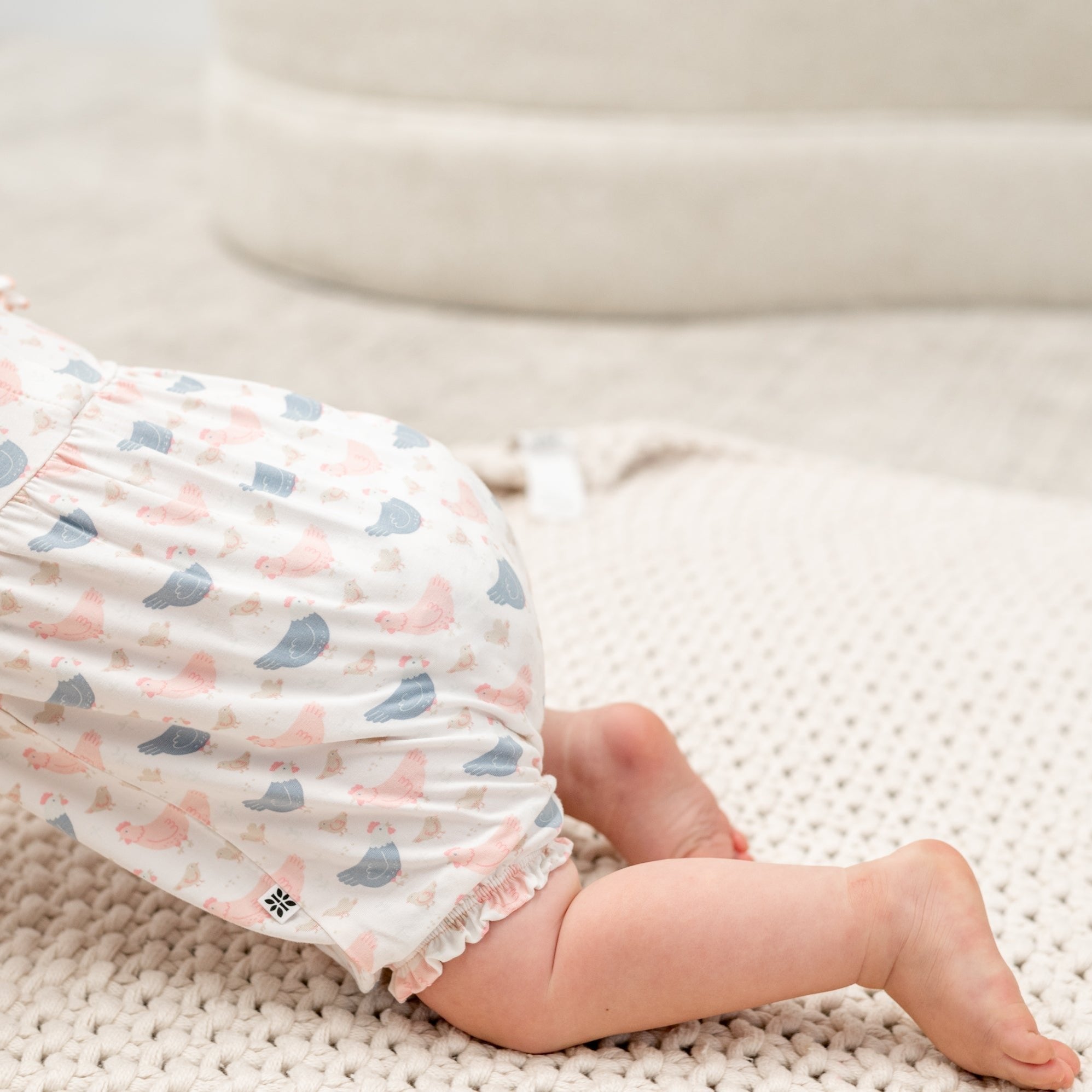 Close-up of pastel bird print romper leg with ruffle hem detail