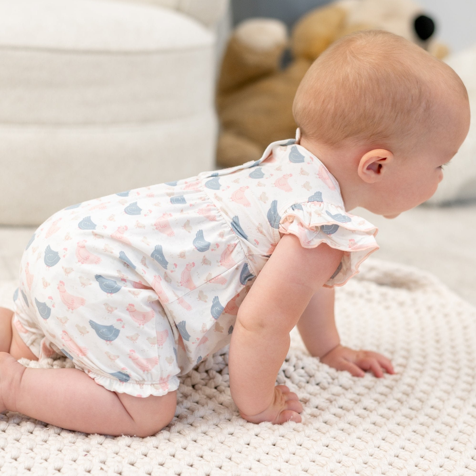 Backless-style baby romper with pastel bird print, ruffle trim, and short romper legs