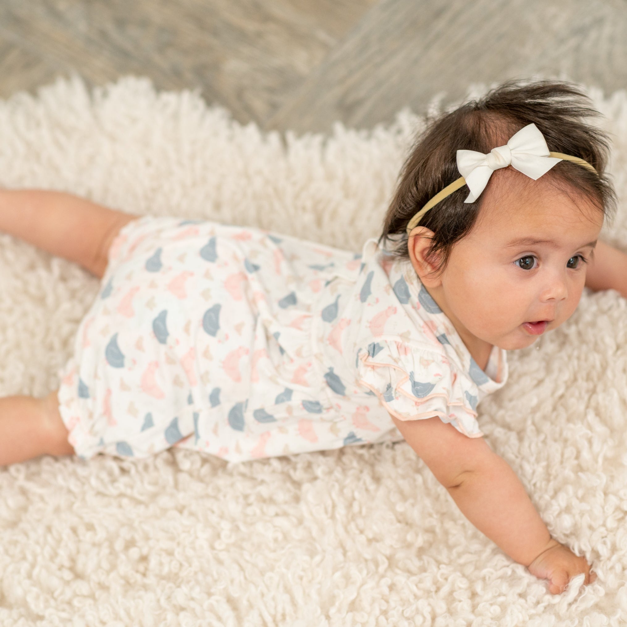 Pastel bird print baby romper with ruffled sleeves and white bow headband look