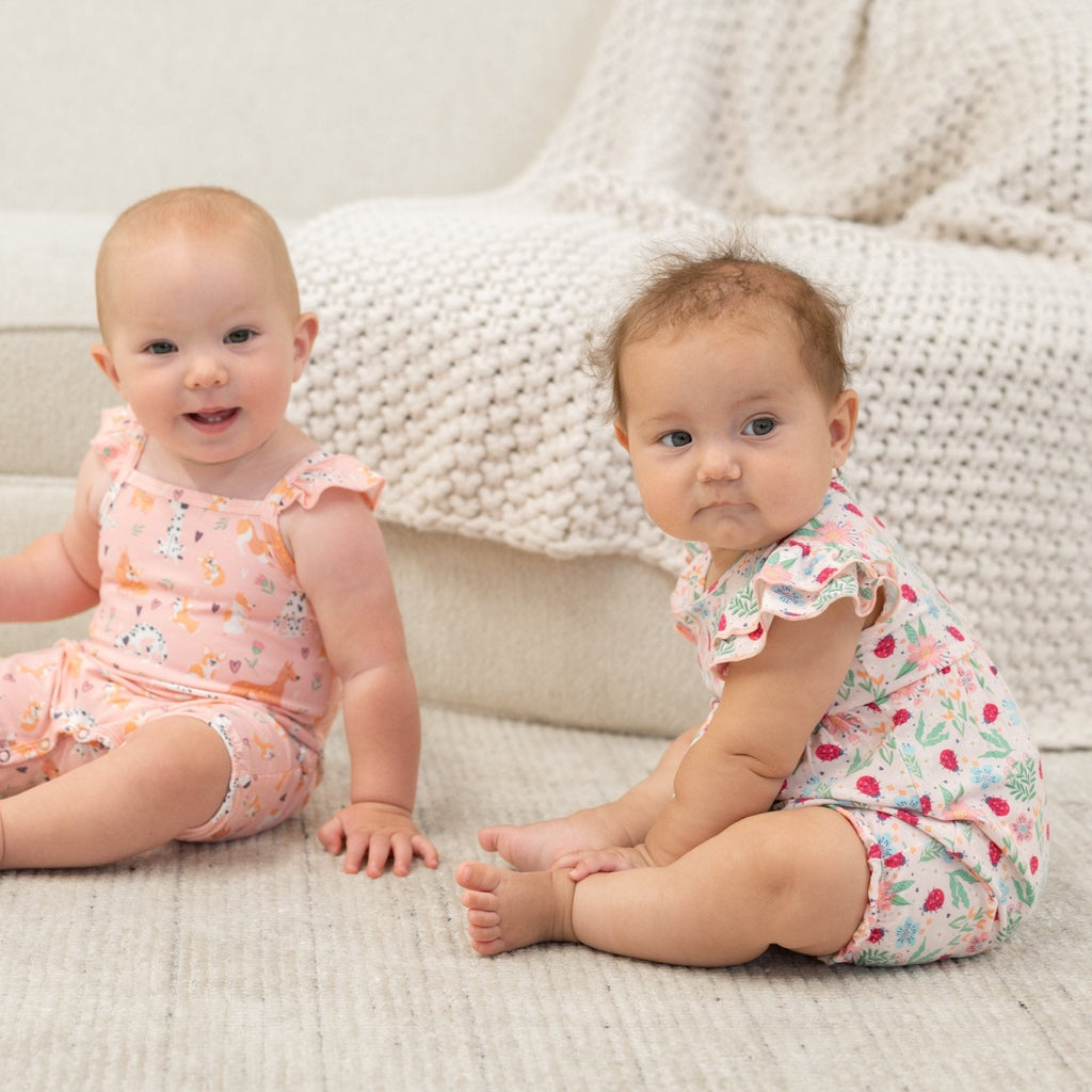 Baby ruffle romper with pink, green, and blue floral and ladybug print, flutter sleeves
