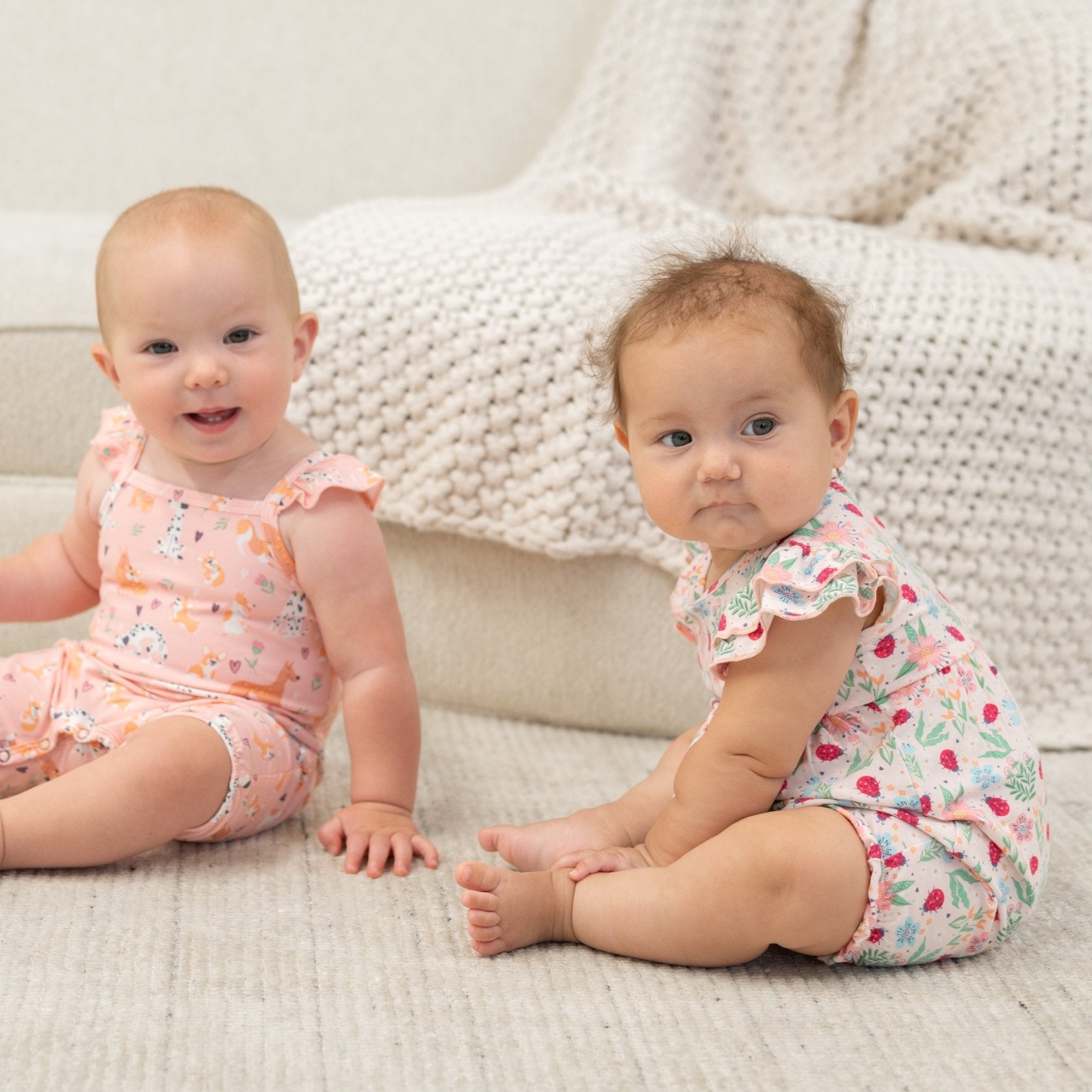 Baby ruffle romper with pink, green, and blue floral and ladybug print, flutter sleeves