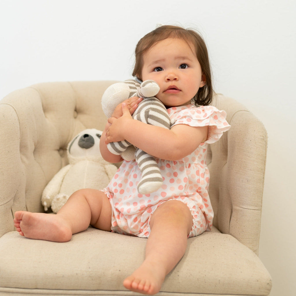 Baby girl wearing pink-and-white polka dot ruffle romper with flutter sleeves
