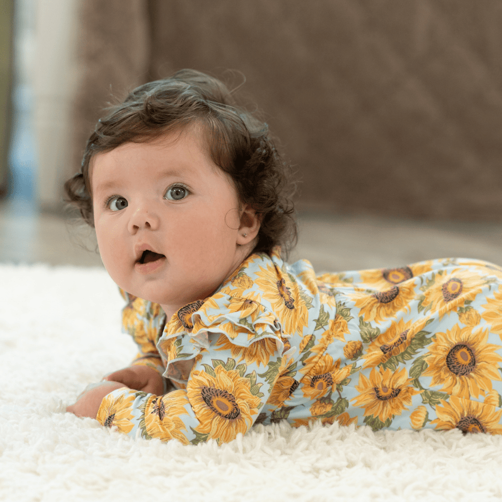 Sunflower print flutter-sleeve romper in light blue, orange-yellow flowers across the fabric