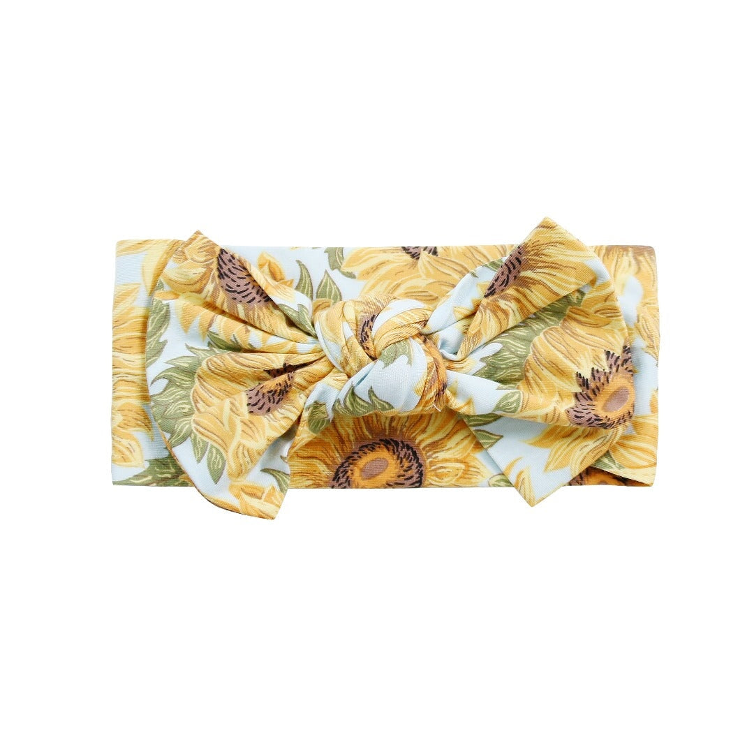 Sunflower print knotted bow headband, light blue base with yellow floral pattern
