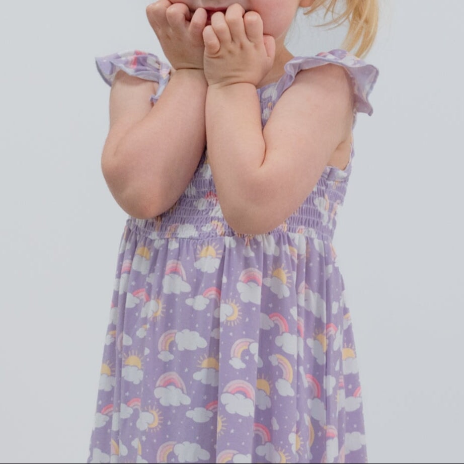 Girls lavender smocked dress with rainbow-cloud print, flutter straps, back view