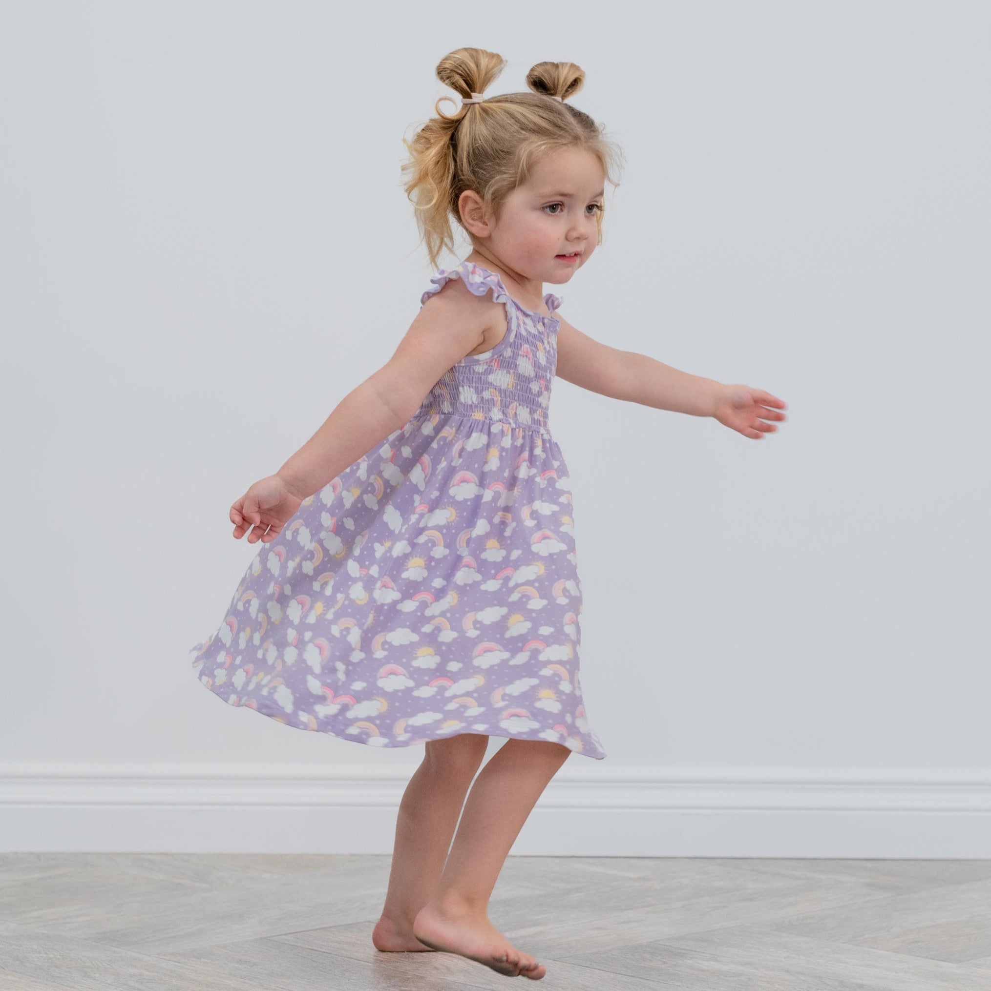 Girls lavender rainbow-cloud smocked dress with ruffled shoulder straps, side view