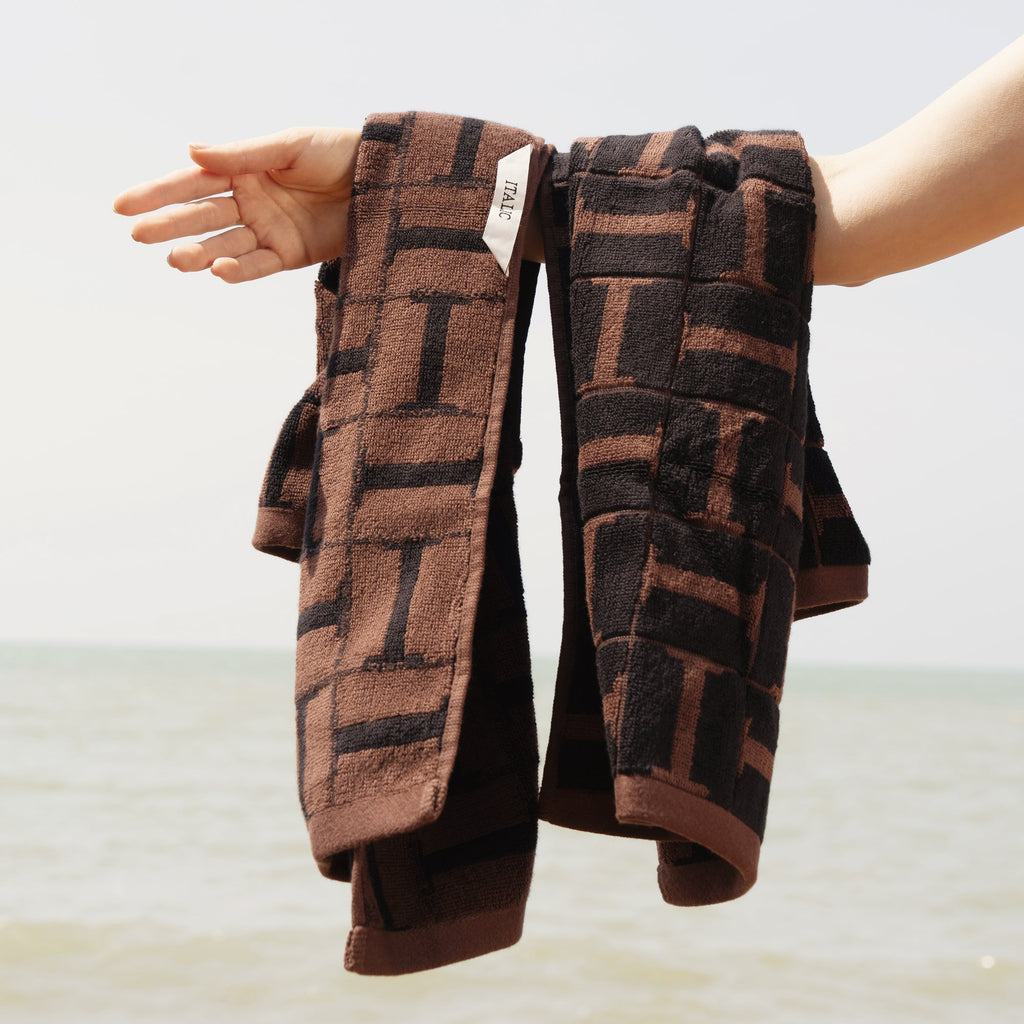 Two rolled cotton towels held in hands, tobacco brown and black plaid